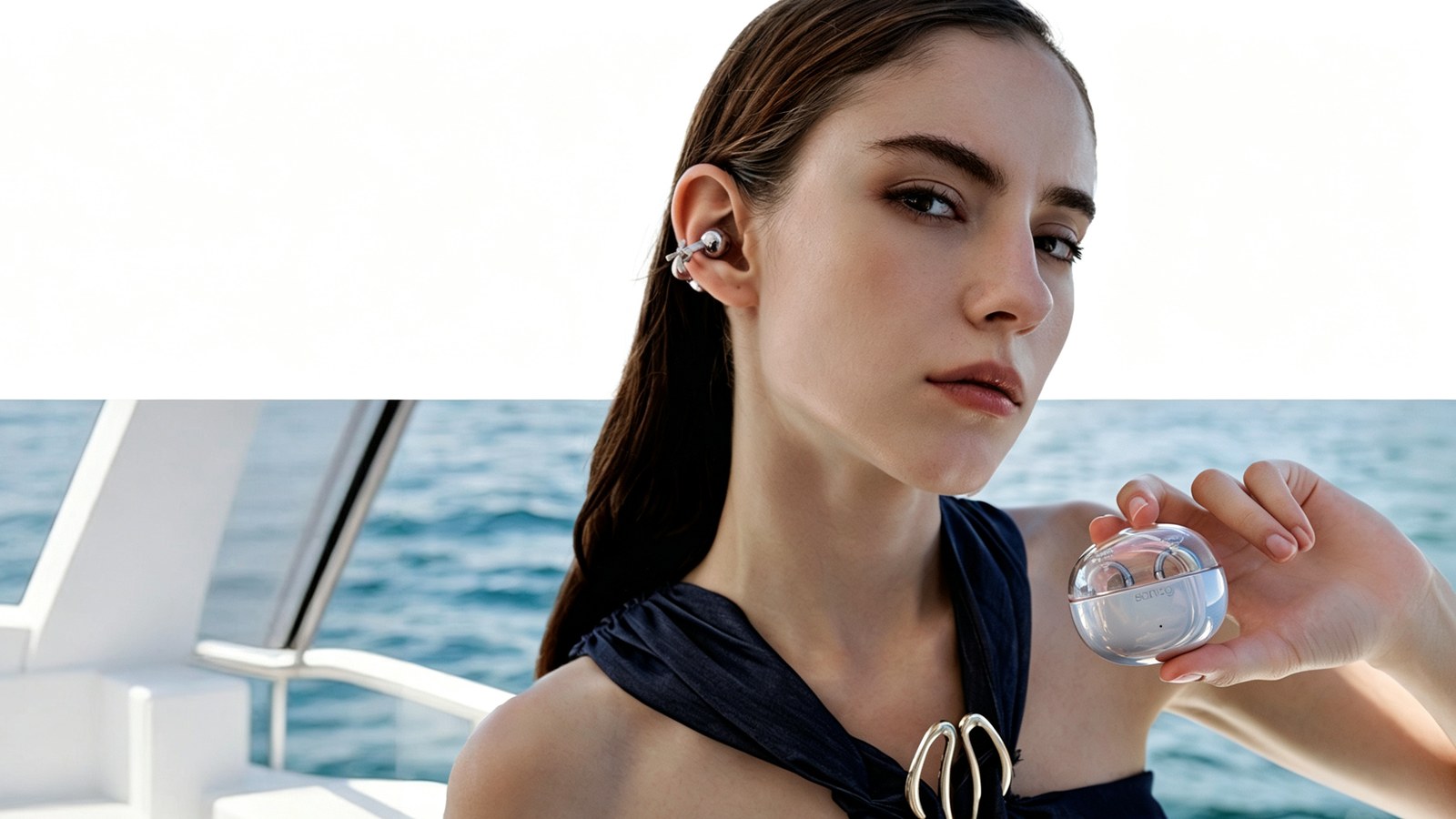 Woman wearing a silver clip-on open-ear earbud and holding a transparent charging case